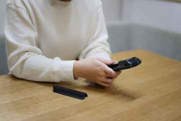 リモコンの電池を回転させる女性