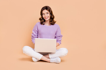 Full length photo of adorable glamour lady sit floor dream buy new netbook look empty space cool offer isolated on beige color background