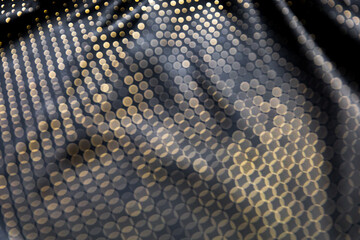Defocused blurred golden polka dot pattern on black folded fabric as background
