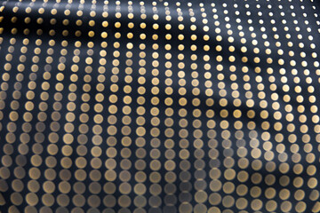 Defocused blurred golden polka dot pattern on black folded fabric as background