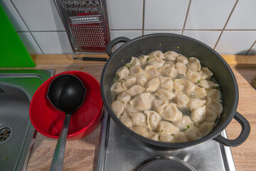 Cooking dumplings with meat by boiling in water in a pan, details, closeup