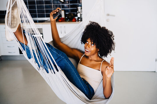 Happy black woman taking selfie on hammock