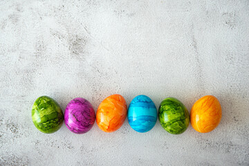 Top view of multicolored colorful Easter eggs in sunlight with shadows over gray textured background. Happy Easter greeting card.