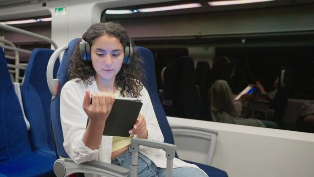 Girl train passenger spending trip time with watching movies on tablet PC