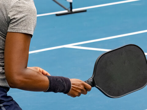 Pickleball paddle in the ready position as held by a Black woman