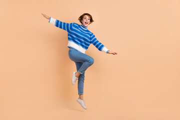Full size portrait of overjoyed cheerful girl jumping have good mood isolated on beige color...