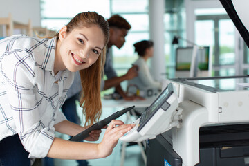 happy young female technician working on photocopier