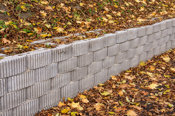 A retaining wall made of concrete elements protects the roadway and pavement from sliding down the...