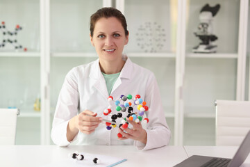 A happy woman, a scientist holds a model of a molecule