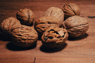 heaps of walnuts, one of which has been opened, waiting to be eaten on a wooden table	