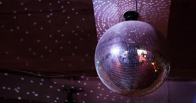 The silver disco ball is spinning and white spots glow beautifully around.
