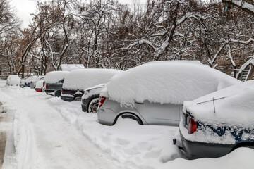 Snow on cars in the morning. Winter season and icy cars on the road. Vehicles covered with snow in...