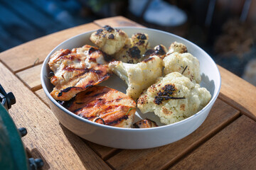 grilling chicken filet and cauliflower steaks at a winter day on the balcony