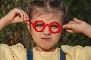 Portrait of capricious funny little girl in red fake glasses
