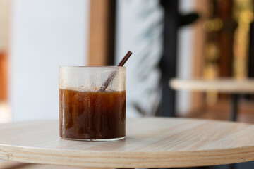 A glass of coffee, Iced Americano, serve on the wooden table.