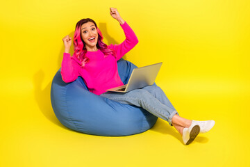 Full length photo of lucky girl dressed vibrant pullover sitting bean bag shopping modern gadget isolated yellow color background