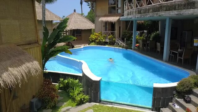 Girl head jump in swimming pool. Magic aerial view flight fly reverse drone.
Bamboo hut hotel resort Swimmingpool Bali, Ubud Spring 2017. High Quality 4k Cinematic footage