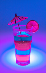 bright rich neon cocktail in a tall glass with an umbrella and a piece of fruit on a neon background. for signage labels screensavers signage menu banners