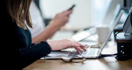 オフィスでのビジネスシーン　ノートパソコンのキーボードを打つ女性　