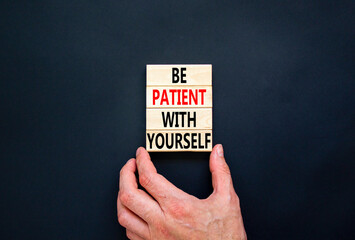 Patient with yourself symbol. Concept words Be patient with yourself on wooden blocks. Beautiful black table black background. Businessman hand. Business patient with yourself concept. Copy space.