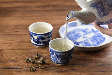 White Ceramic Chinese style Teapot pouring Chinese tea in Ceramic cup. White Ceramic Chinese style Teapot set for tea break time.