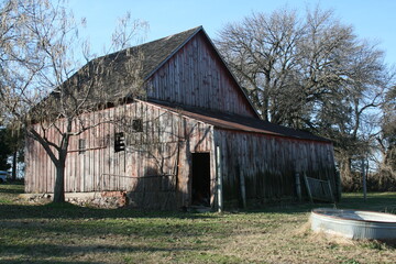 Fototapeta premium You can almost hear the creaking from this old leaning weathered red barn.