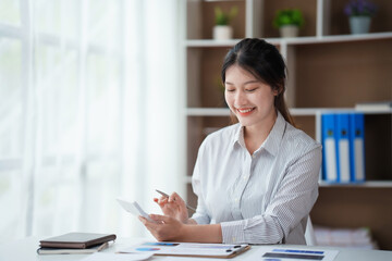 Asian businesswoman working with laptop computer using calculator to calculate business finance and accounting statistics at office.