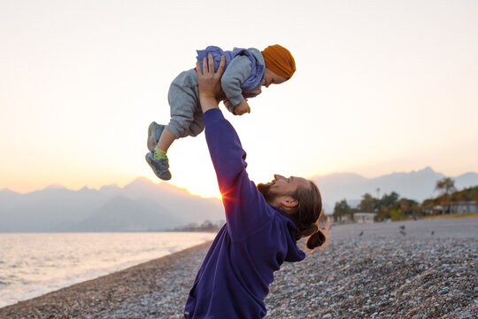 Dad and child are sitting on the beach.