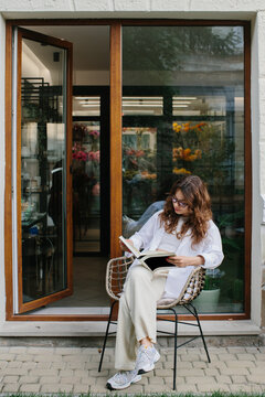 Magazine or book image mockup. A young hipster girl reads a magazine against the background of a cozy coffee shop.