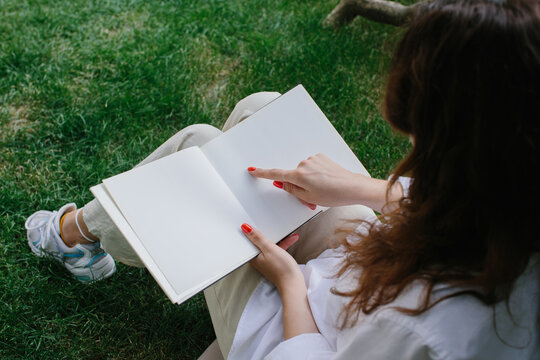 Magazine or book image mockup. The girl relaxes on the lawn in the courtyard of the coffee shop, reads a book.