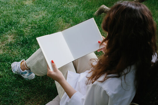 Magazine or book image mockup. The girl relaxes on the lawn in the courtyard of the coffee shop, reads a book.