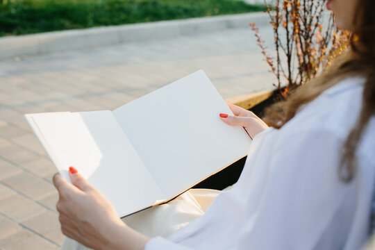 Magazine or book image mockup. A girl reads a book sitting on a bench on a city street at sunset.