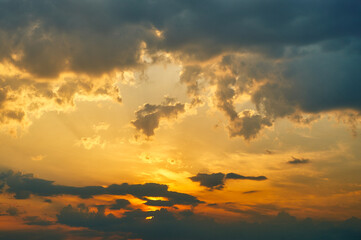 Summer sky at sunset, golden light from the sun colors the sky, thunderclouds and cumulus clouds give the sky a dramatic look, sky landscape