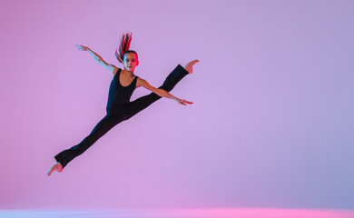 teenage girl in a tight black costume dancing a modern contemporary contemporary dancer isolated on a background in neon light.