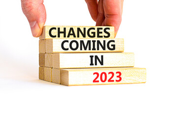 Changes coming in 2023 symbol. Concept word Changes coming in 2023 on wooden blocks. Businessman hand. Beautiful white table white background. Business and changes coming in 2023 concept. Copy space.