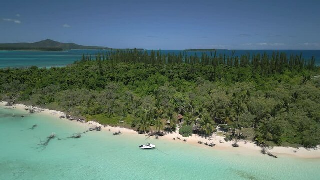 Boats bring tourists to the pristine beach on ilot Moro in the Isle of Pines - pull back aerial reveal