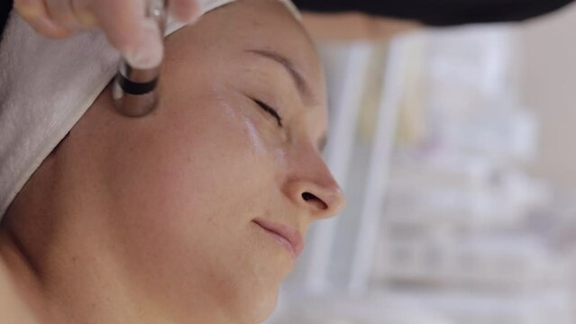 Injection-free mesotherapy or electroporation. Beautician doctor makes client woman face therapy in beauty clinic salon. Girl skin care anti-age spa procedure. Aesthetic cosmetology. Vertical video