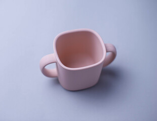 Children's silicone mug isolated on background. Baby feeding and nutrition concept. Top view, flat lay.