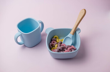A set of children's silicone dishes with corn flakes. Baby feeding and nutrition concept. Top view, flat lay.