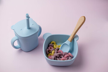 A set of children's silicone dishes with corn flakes. Baby feeding and nutrition concept. Top view, flat lay.