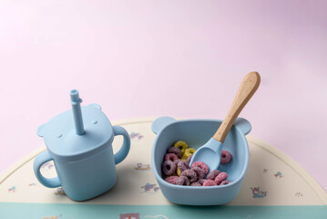 A set of children's silicone dishes with corn flakes. Baby feeding and nutrition concept. Top view, flat lay.
