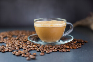 hot delicious aromatic cappuccino coffee in a glass transparent cup on a background of coffee beans