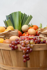 Organic vegetables bamboo basket full of fresh vegetables, fruit and eggs from free-range chickens, side view, against white background, cropped 