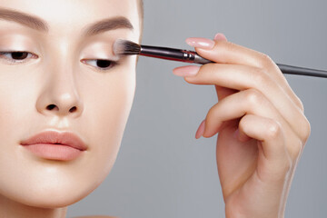 Young woman applies eye shadow with brush