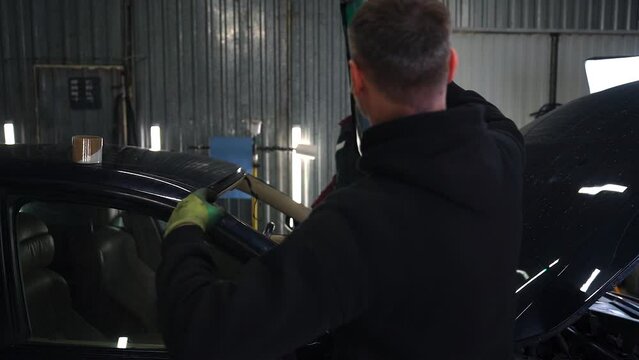 Installing a new windshield on a car. The guys carry glass in their hands .Slow Motion.