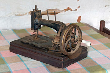 Vintage sewing machine on table and cob wall on background