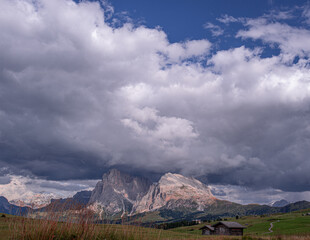 Heavy cloud on top of Sassolungo and Sassopiatto mountains as seen from Alp di Siusi high mountain plateau , Seiser Alm, Dolomites, Trentino, Alto Adige, Italy