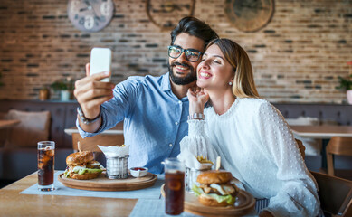 Fototapeta na wymiar Young couple sitting in a cafe, having breakfast. Love, dating, food, lifestyle concept