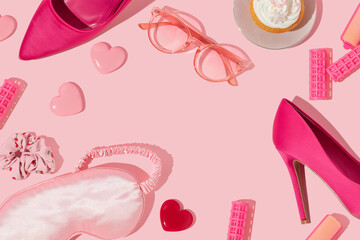 Valentines day creative romantic layout with high heels, hearts, hair rollers, sleep mask, scrunchie, cupcake and eyeglasses on pastel pink background. 80s or 90s retro fashion aesthetic love concept