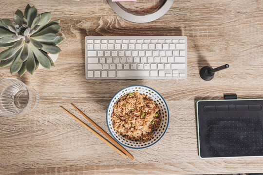 Top View Of A Bowl Of Oriental Rice On The Background Of The Work Table. Time To Enjoy Lunch At Work